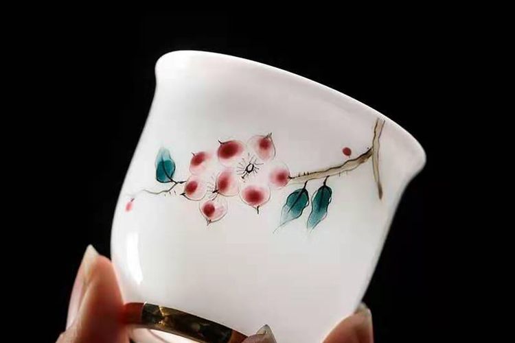 手持白瓷梅花杯(黑底特写)