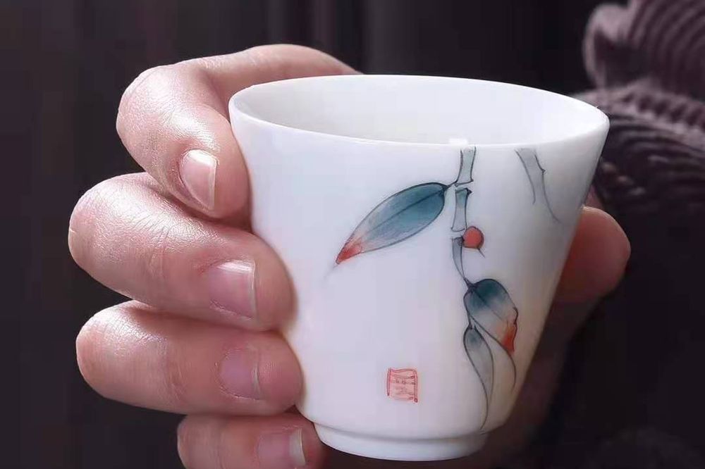 白瓷花鸟杯手持实拍：白瓷底的彩绘多是釉上或釉下贴花，多色手绘的层次感仍要回到景德镇这条线